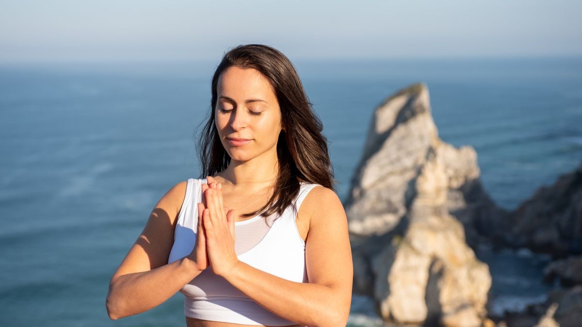 Woman meditating outdoors by the ocean in Portugal, promoting relaxation and mindfulness.